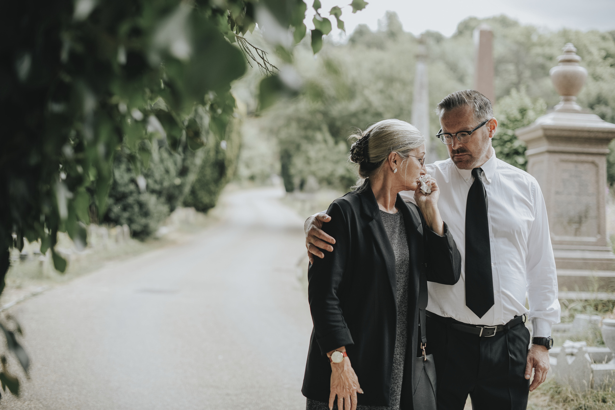 A man and woman walk through a graveyard.  