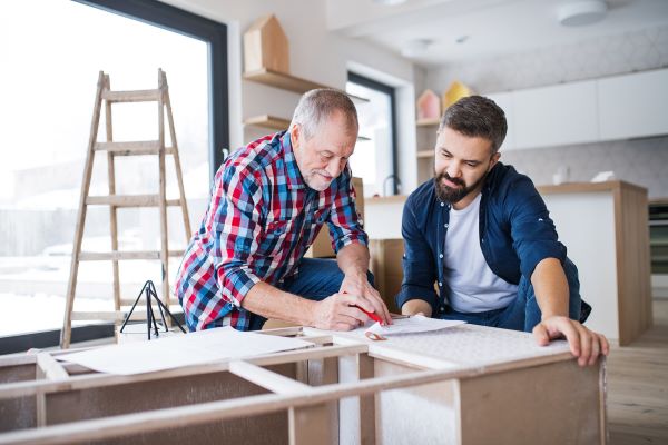 senior and young man measure wood for home renovation 
