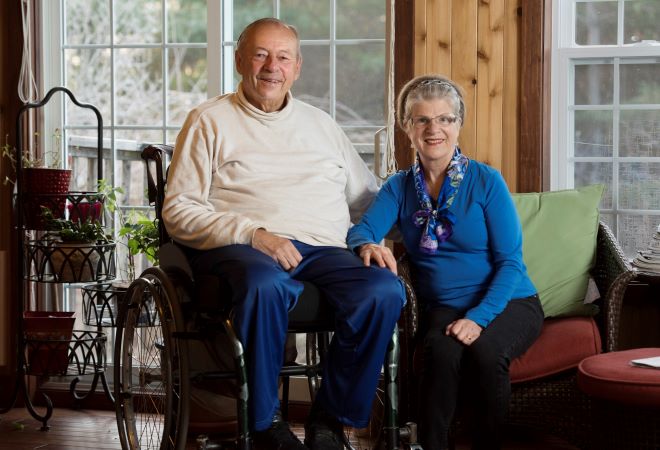 older man in wheelchair sits next to older woman 