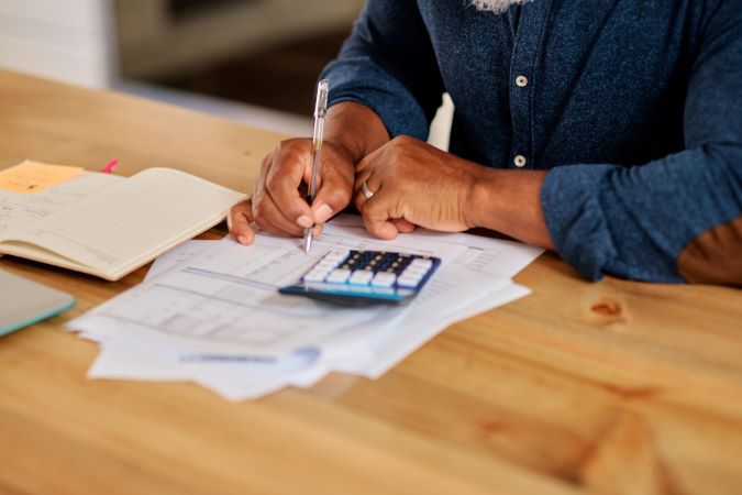 Quelqu'un regarde des papiers avec une calculatrice.