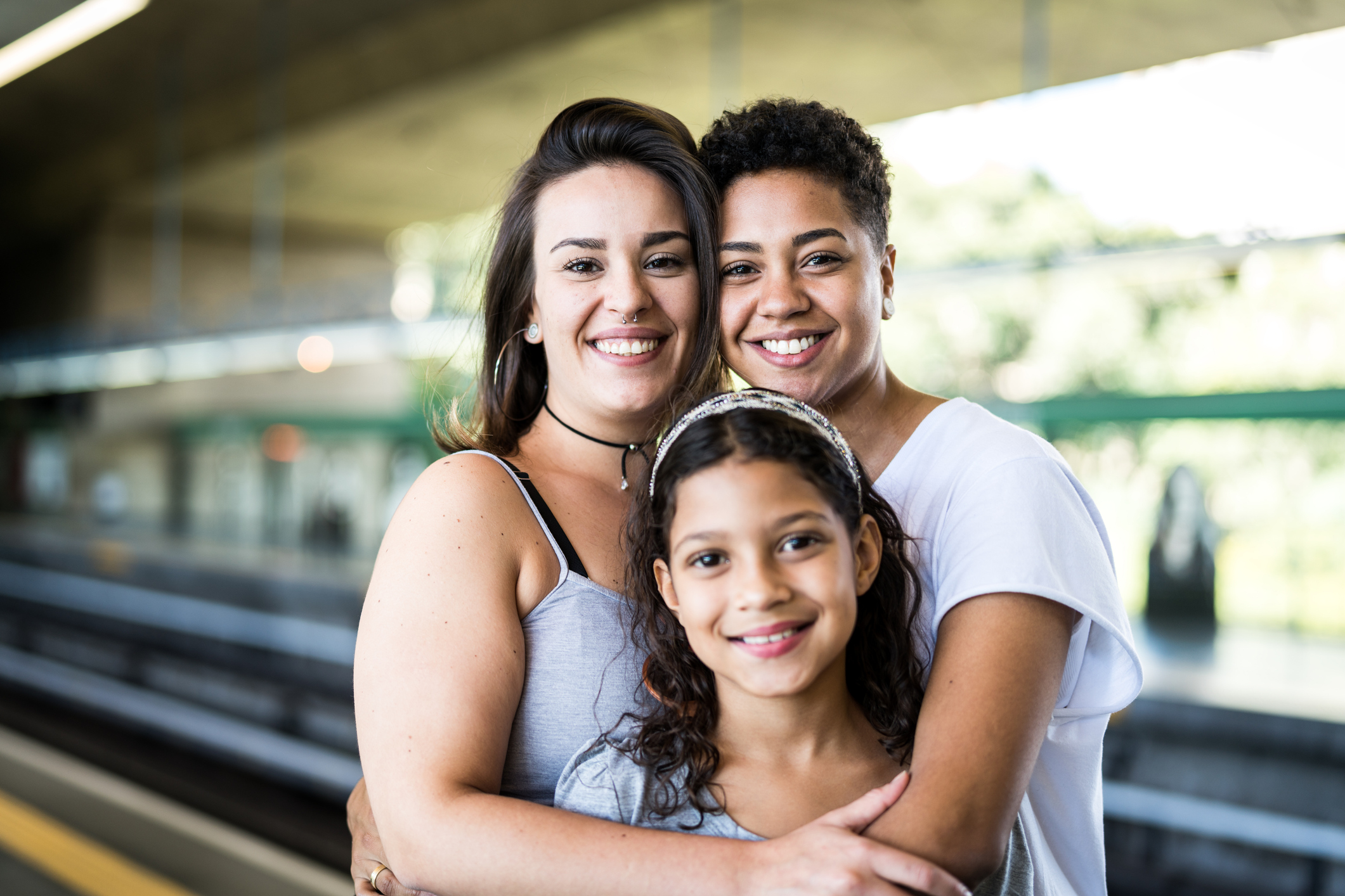 two mothers and their daughter smile at the camera