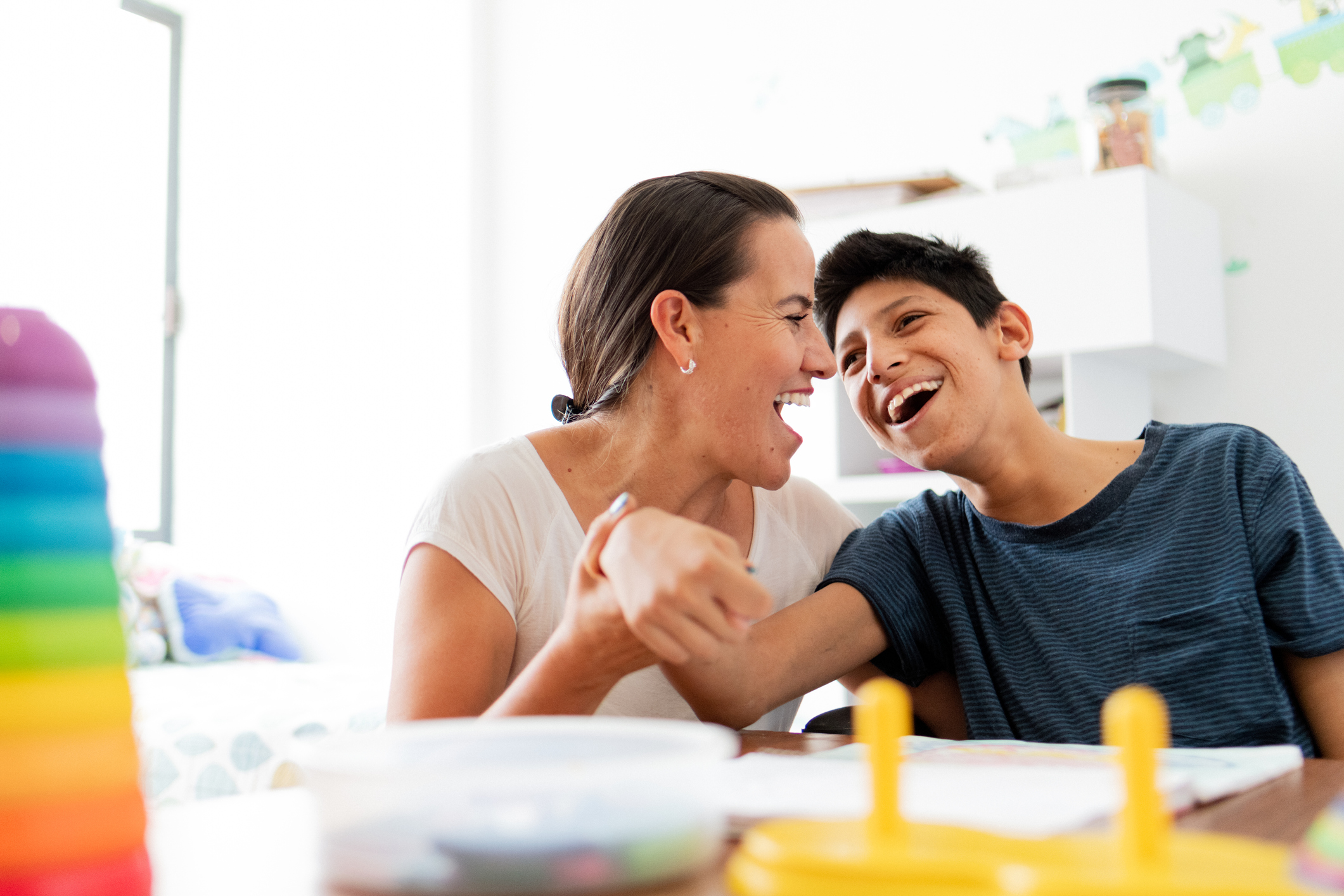 Woman laughs with teenaged boy with cerebral palsy