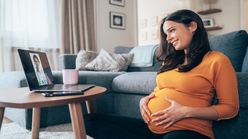 Femme enceinte regardant un ordinateur.