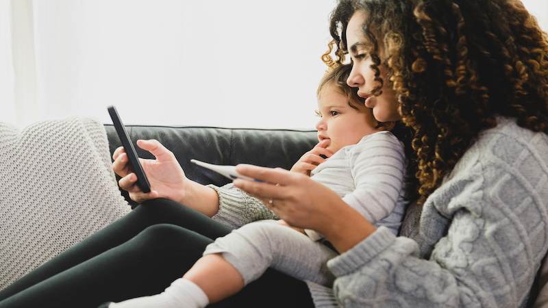 Mom holding a cellphone with a baby.