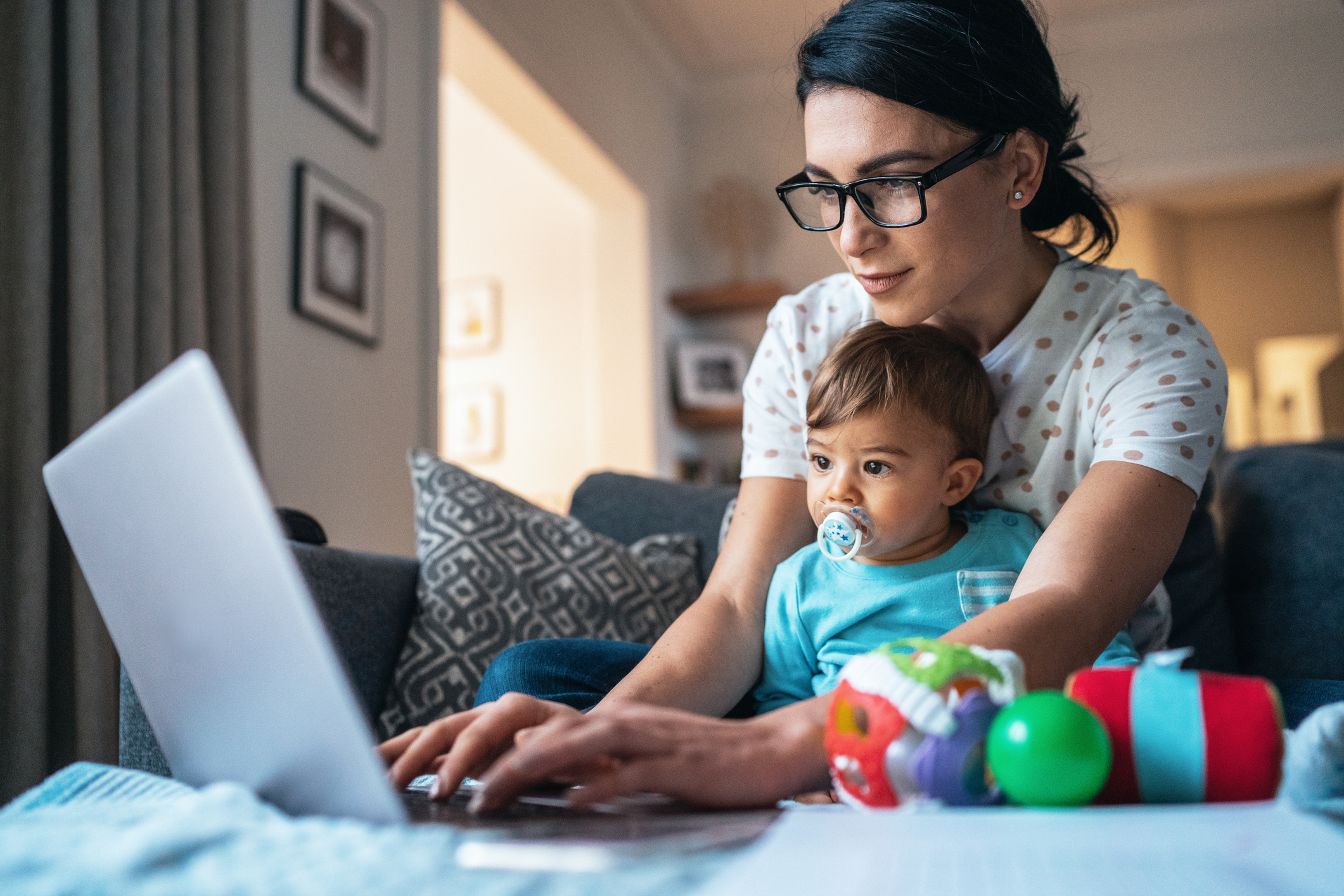 Mother with infant on her lap using laptop to browse the internet.