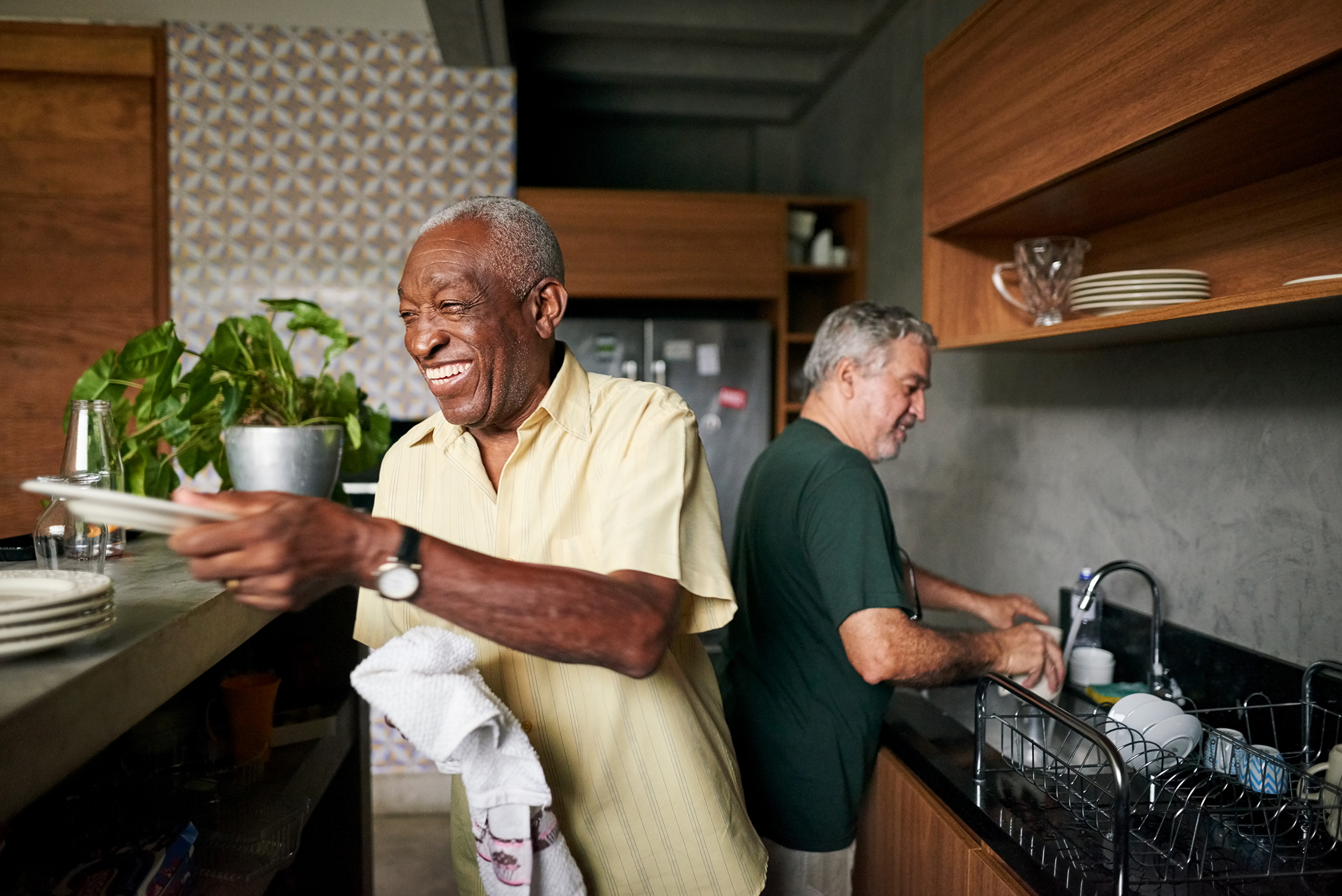 Two people in the kitchen doing dishes and having a friendly conversation.