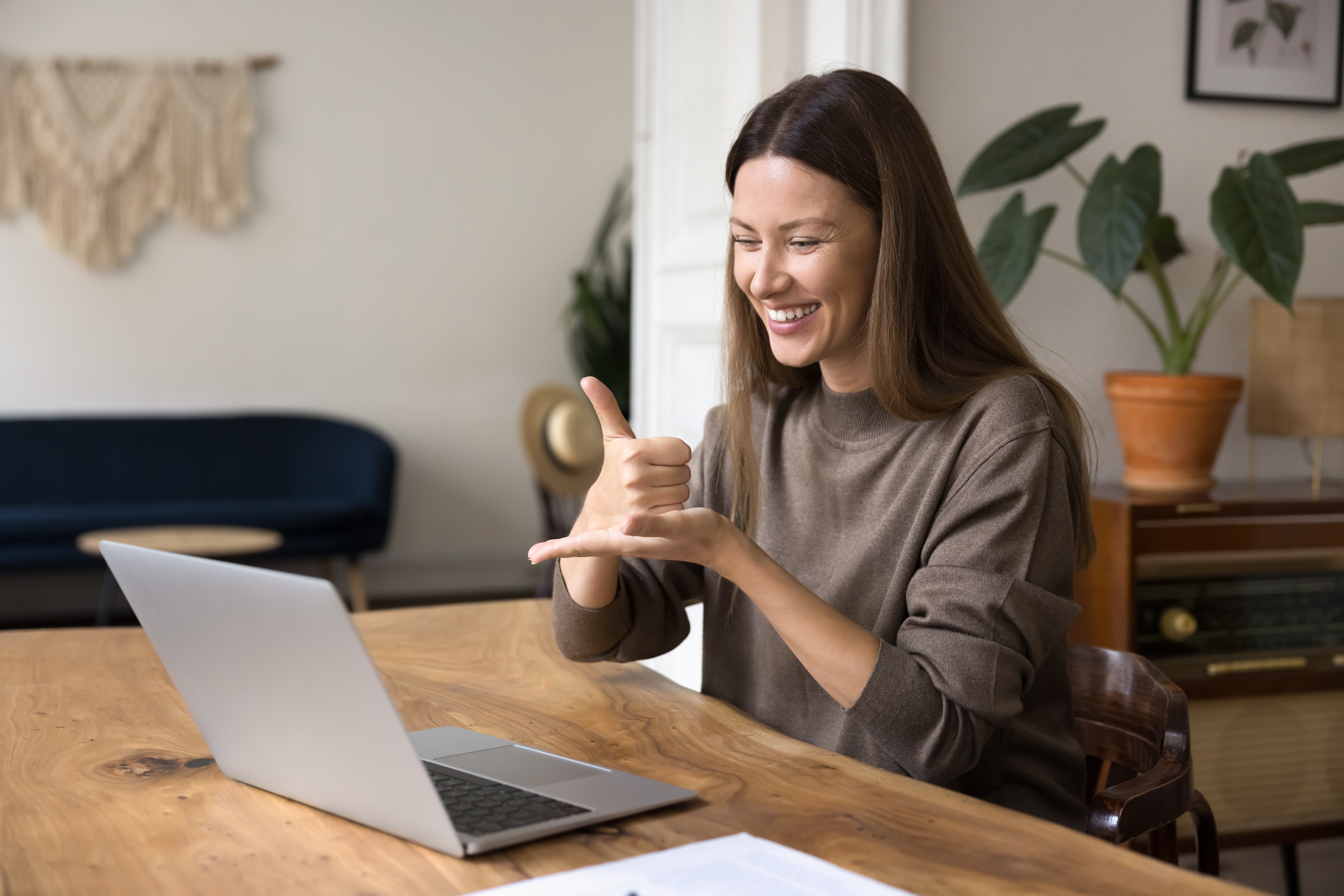 Smiling woman using sign language during a video call on her laptop at home